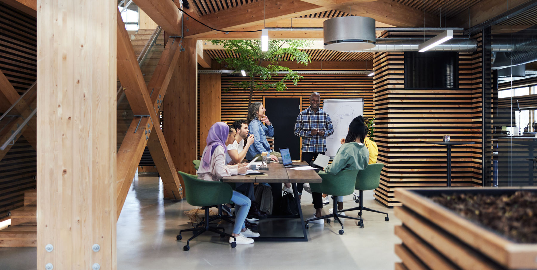 Team meeting around a table in a bright, wood-panelled open office