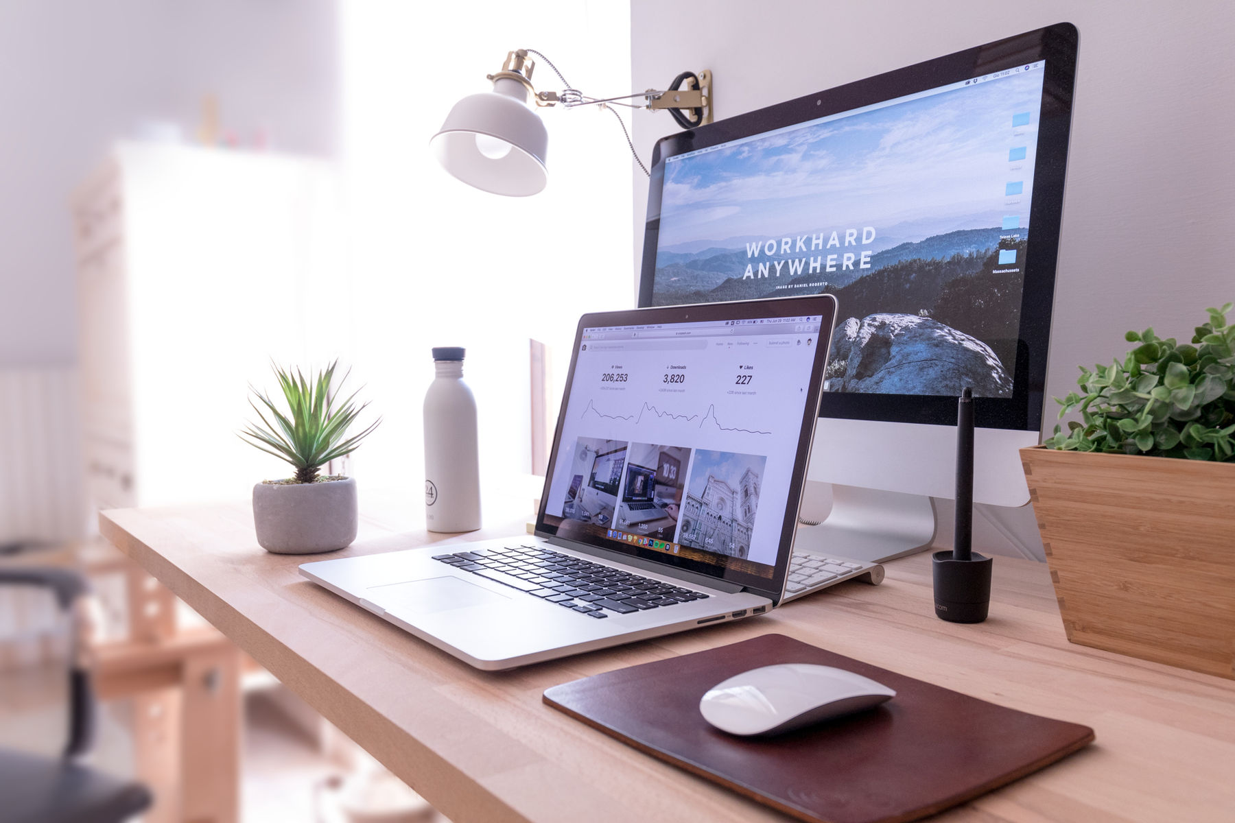 Laptop and desktop monitor on a bright wooden desk